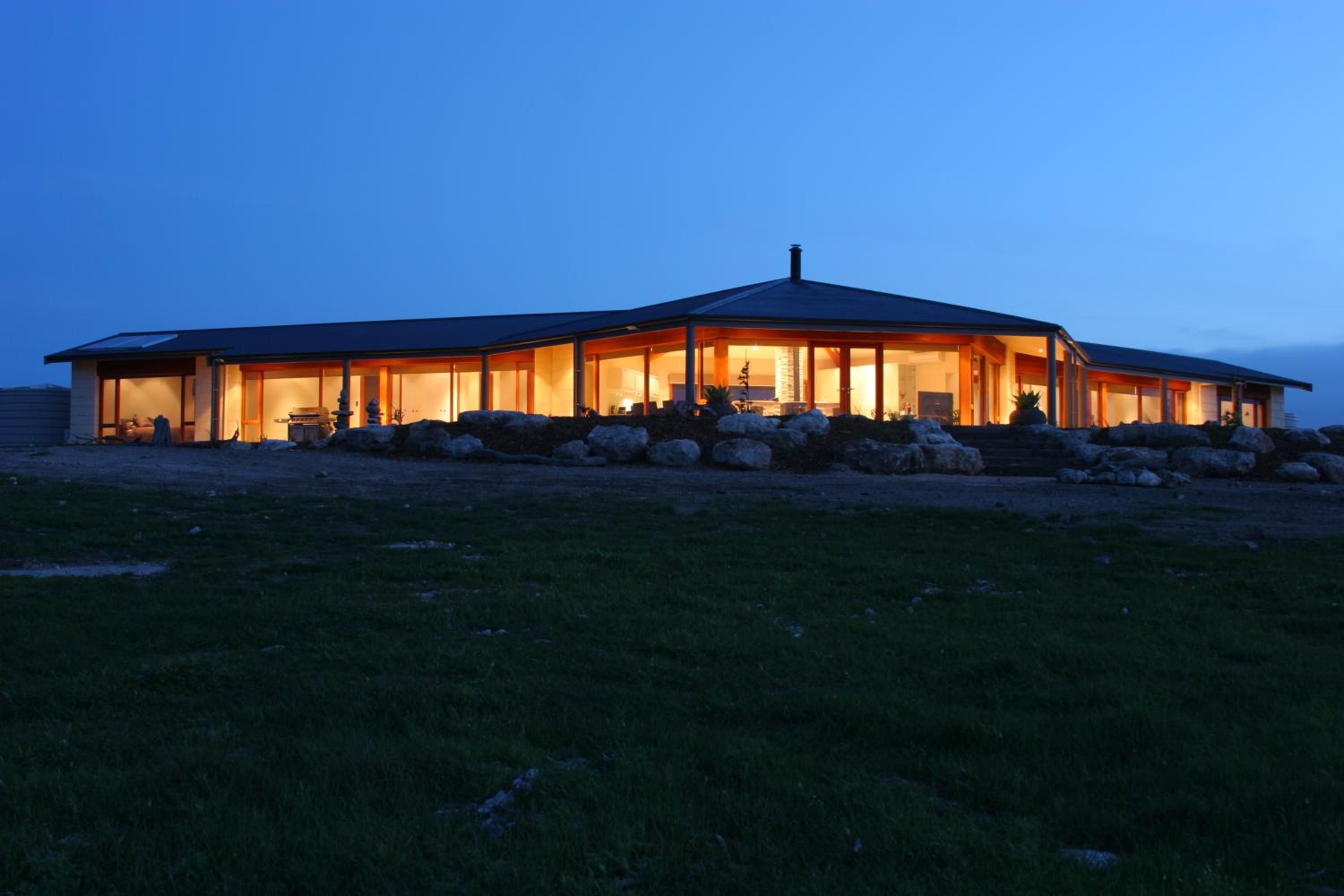 A modern house with a large open porch, a stone fireplace, and a well-maintained lawn.