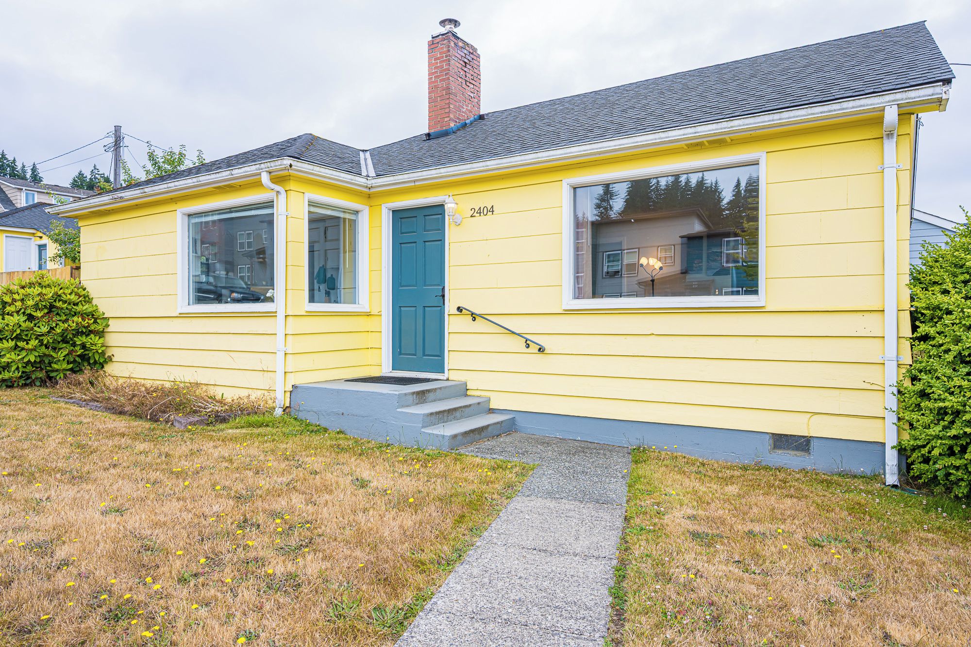 A yellow single-story house with a blue door, numbered 2404, and a small front porch.
