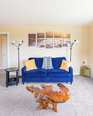 A room with a blue sofa, a wooden coffee table, and a wall with four paintings. - Sunny Hills 2-bedroom house in welcoming Port Angeles for your getaway (Port Angeles)