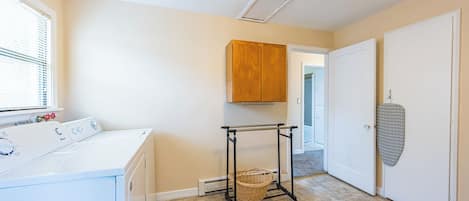 A laundry area with a washing machine, a drying rack, and a wooden cabinet.