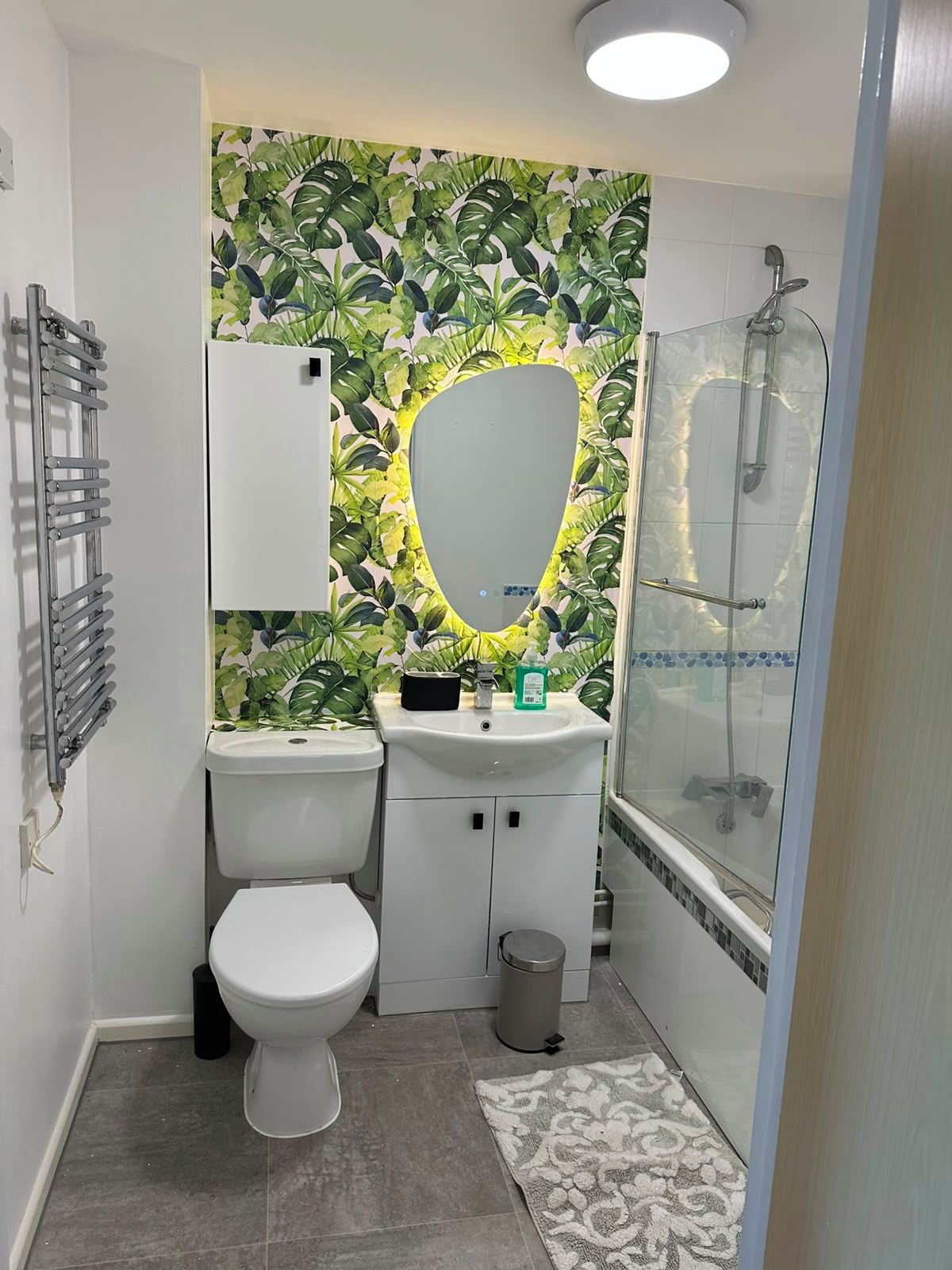 Un baño con inodoro, lavabo, espejo, ducha y un cubo de basura.