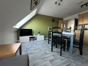 A modern living space with a TV, dining area, and kitchen. - 5 minutes to the theme park! Family-sized condo with game room & deck (Bristol)