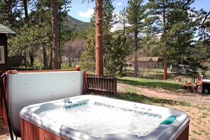 A hot tub outdoors surrounded by trees and a wooden fence. - Triple R Cottages (Estes Park)