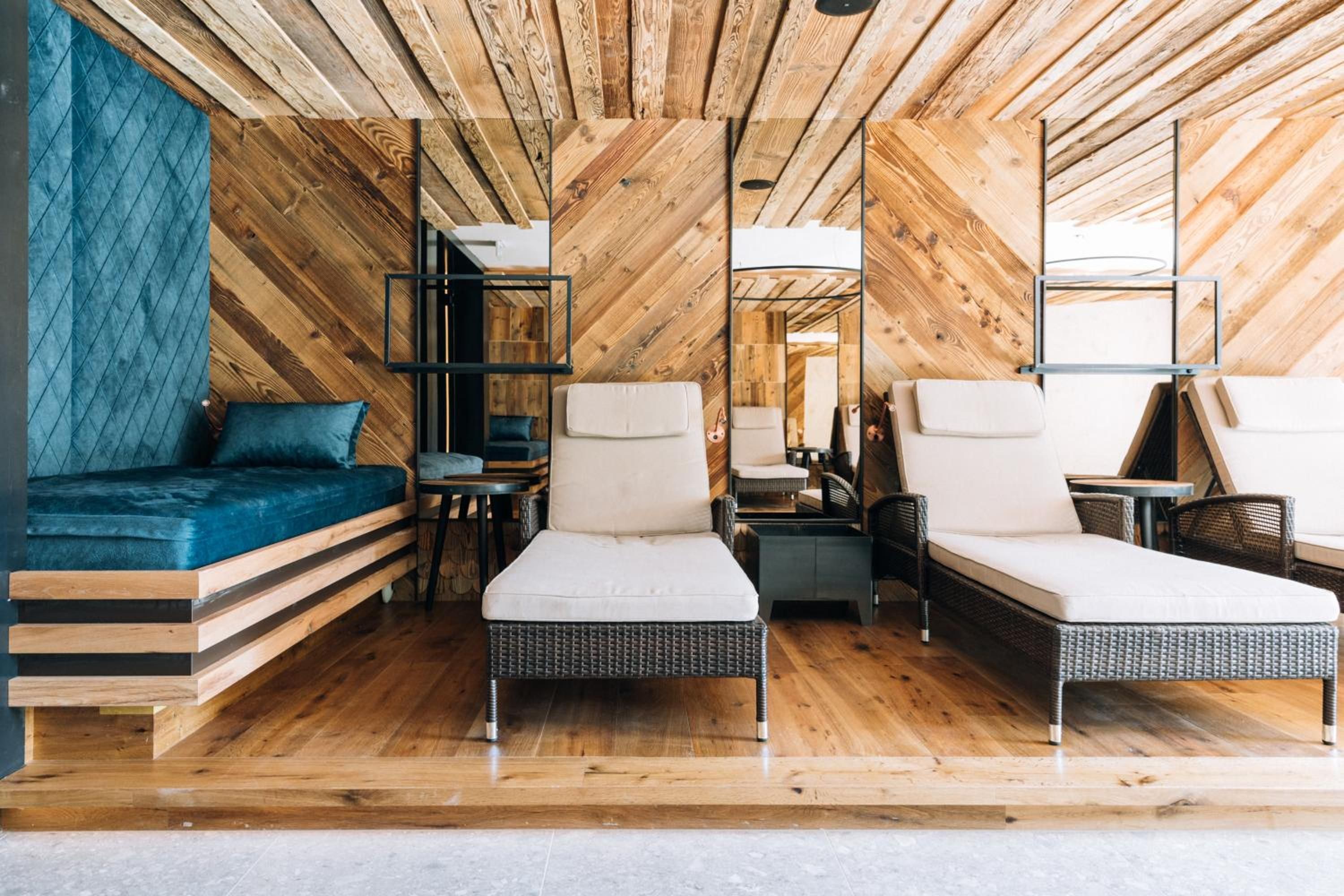 Ein modernes Interieur mit Holzboden, einer Couch, zwei Stühlen, einem kleinen Tisch und einem Spiegel.