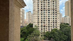 Un edificio de gran altura con múltiples balcones, rodeado de vegetación y otros edificios.