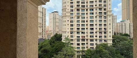 A high-rise building with multiple balconies and a view of surrounding greenery.