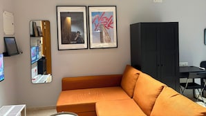 Una sala de estar moderna con un sofá, un mueble negro y dos cuadros en la pared.