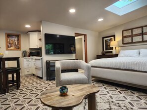 Une chambre d’hôtel équipée d’un lit, d’un bureau, d’une chaise, d’une petite table et d’un téléviseur.