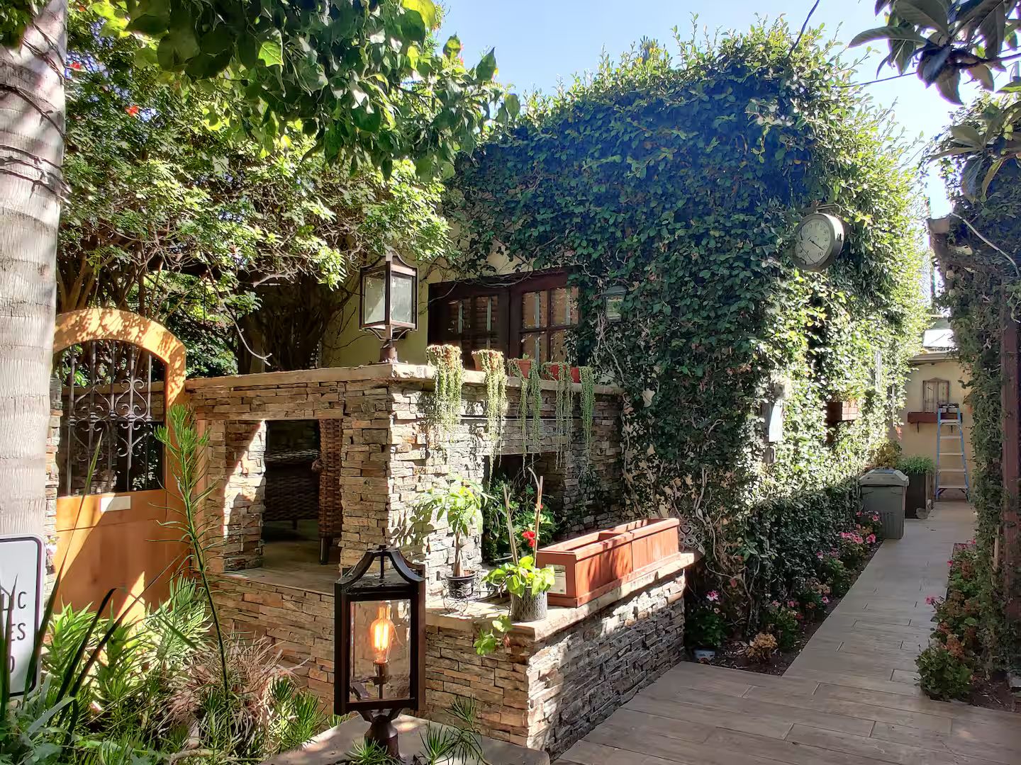 A stone building with a brick archway, a lantern, and a pathway leading to a door.