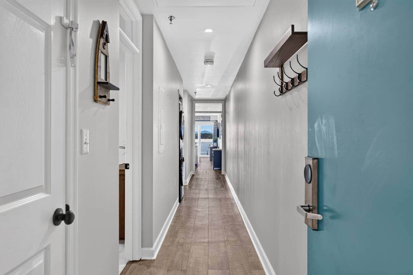 A hallway with white doors, a blue wall, and a wooden floor.