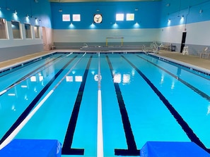 Piscina com pistas demarcadas, plataforma de mergulho e área de vestiários.