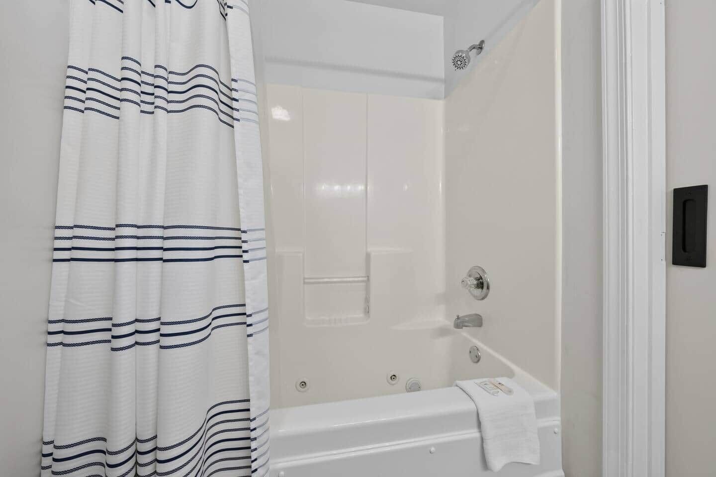 A bathroom with a bathtub, a shower, and a curtain with a striped pattern.
