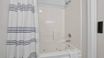 A bathroom with a bathtub, a shower, and a curtain with a striped pattern.