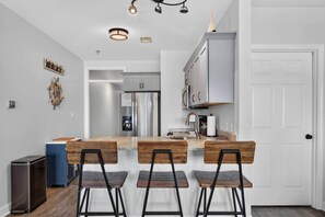 Uma cozinha moderna com ilha central, eletrodomésticos de aço inoxidável e uma porta branca.