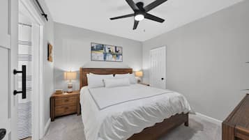 A bedroom with a bed, bedside tables, a ceiling fan, and a door.