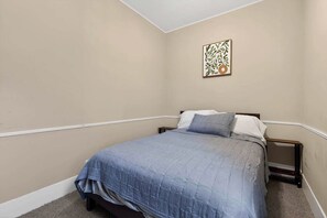 A bedroom with a single bed, a nightstand, and a wall-mounted artwork. - Cozy Southfield Ranch (Southfield)