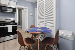 A compact kitchen with a microwave, oven, and a dining area with a table and chairs. - Cozy Southfield Ranch (Southfield)