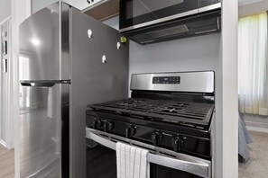 A compact kitchen with a stainless steel refrigerator, a built-in microwave, and a gas stove. - Cozy Southfield Ranch (Southfield)