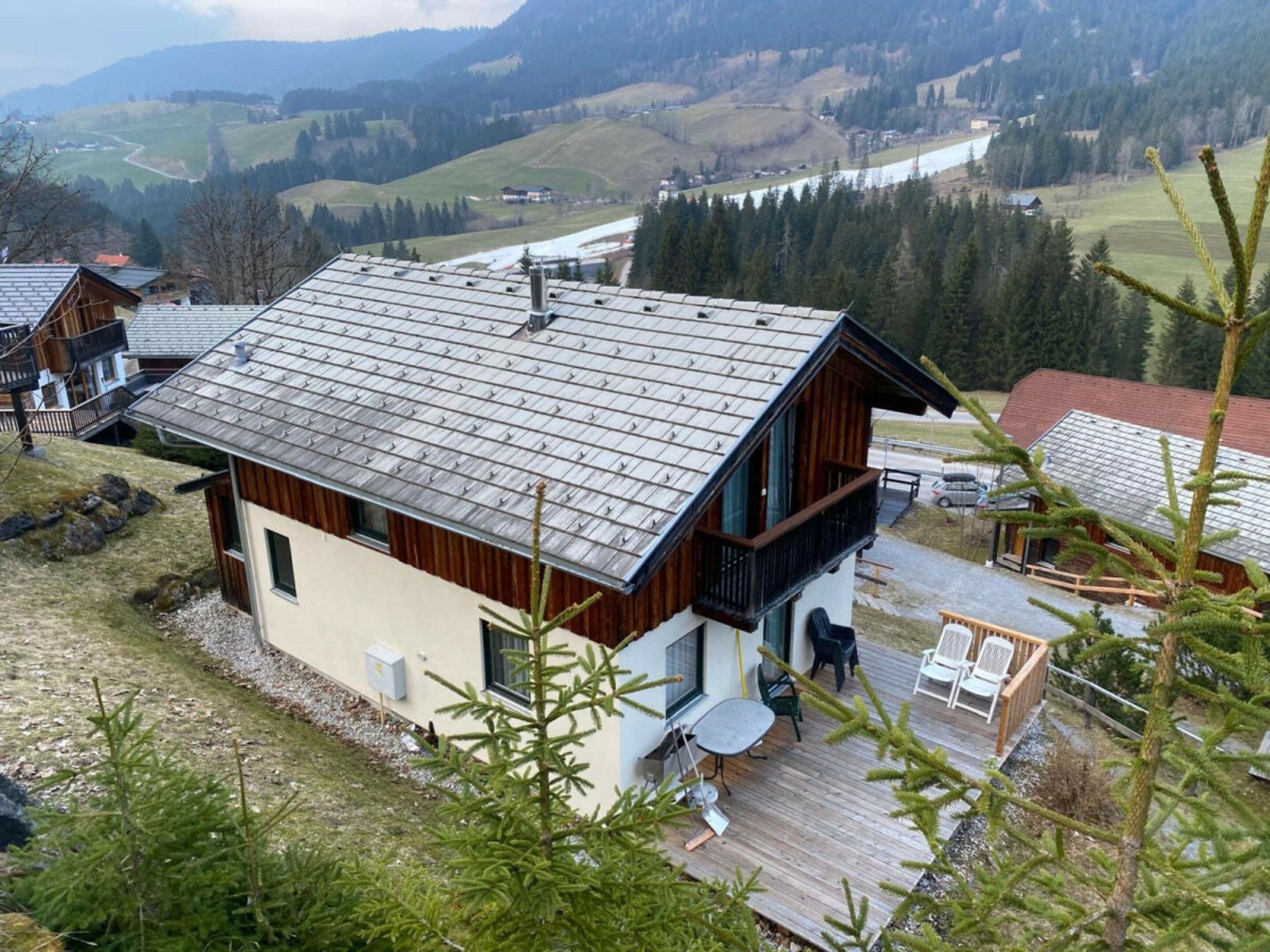 Uma casa moderna com telhado inclinado, varanda e um deck com área de estar externa.