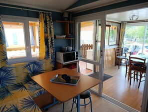 Una habitación con una mesa de madera, un microondas y una ventana con cortinas.