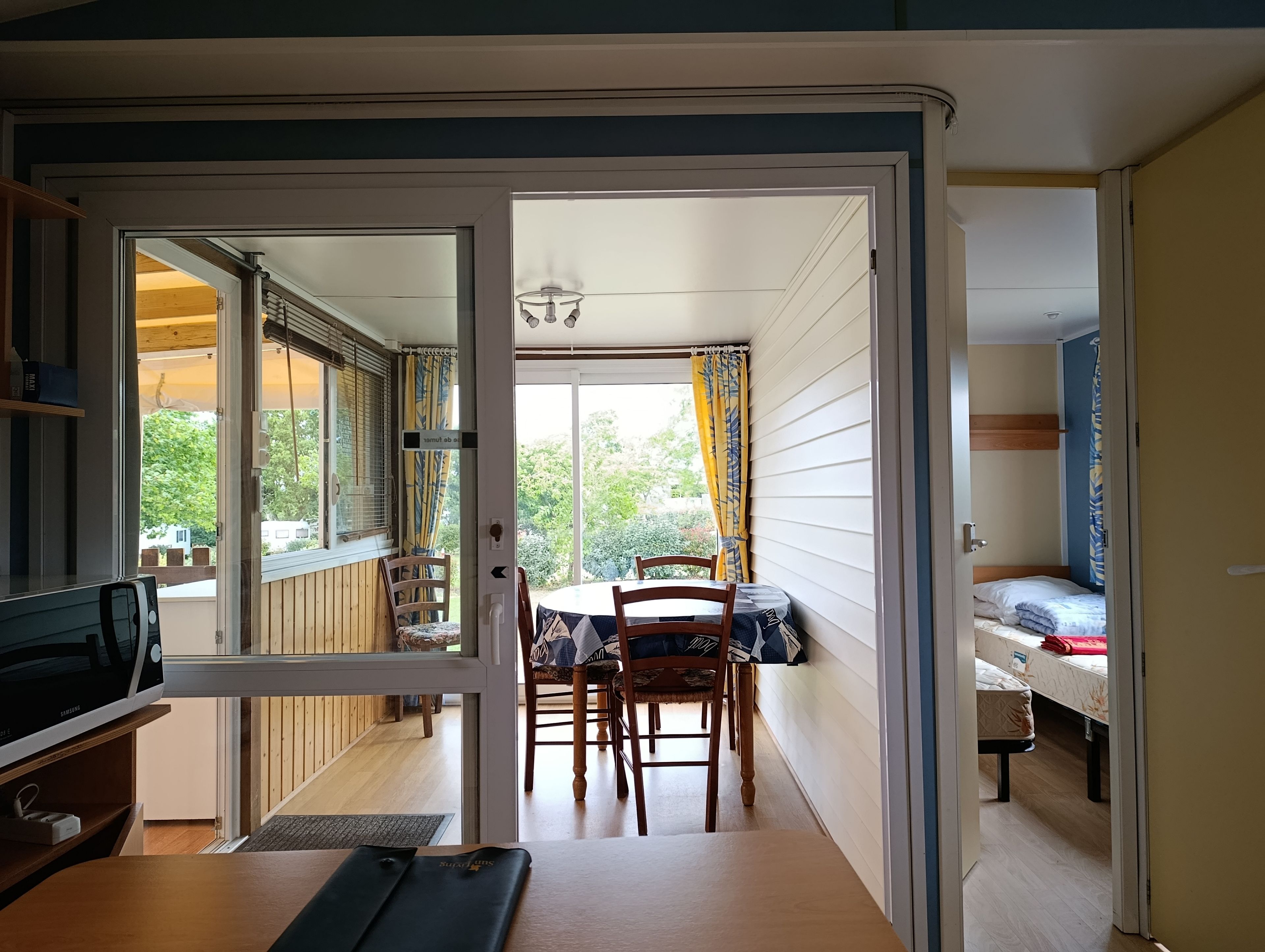 Een kamer met een eettafel en stoelen, een bed en een televisie.