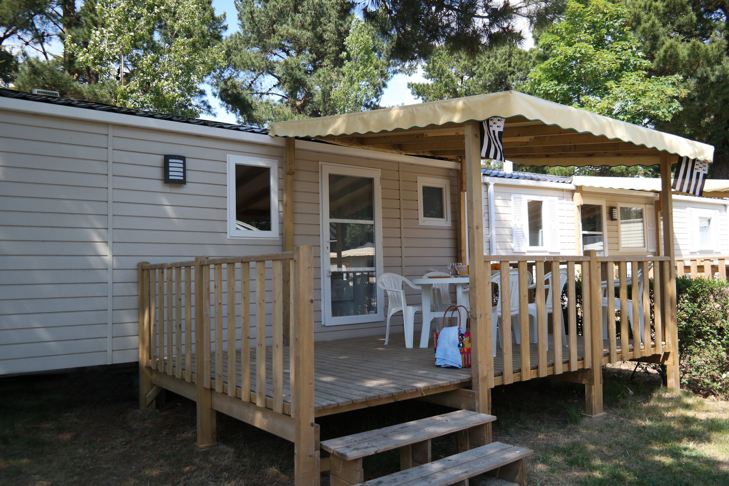 Eine Holzterrasse mit überdachter Sitzgelegenheit, einem Tisch und Stühlen.