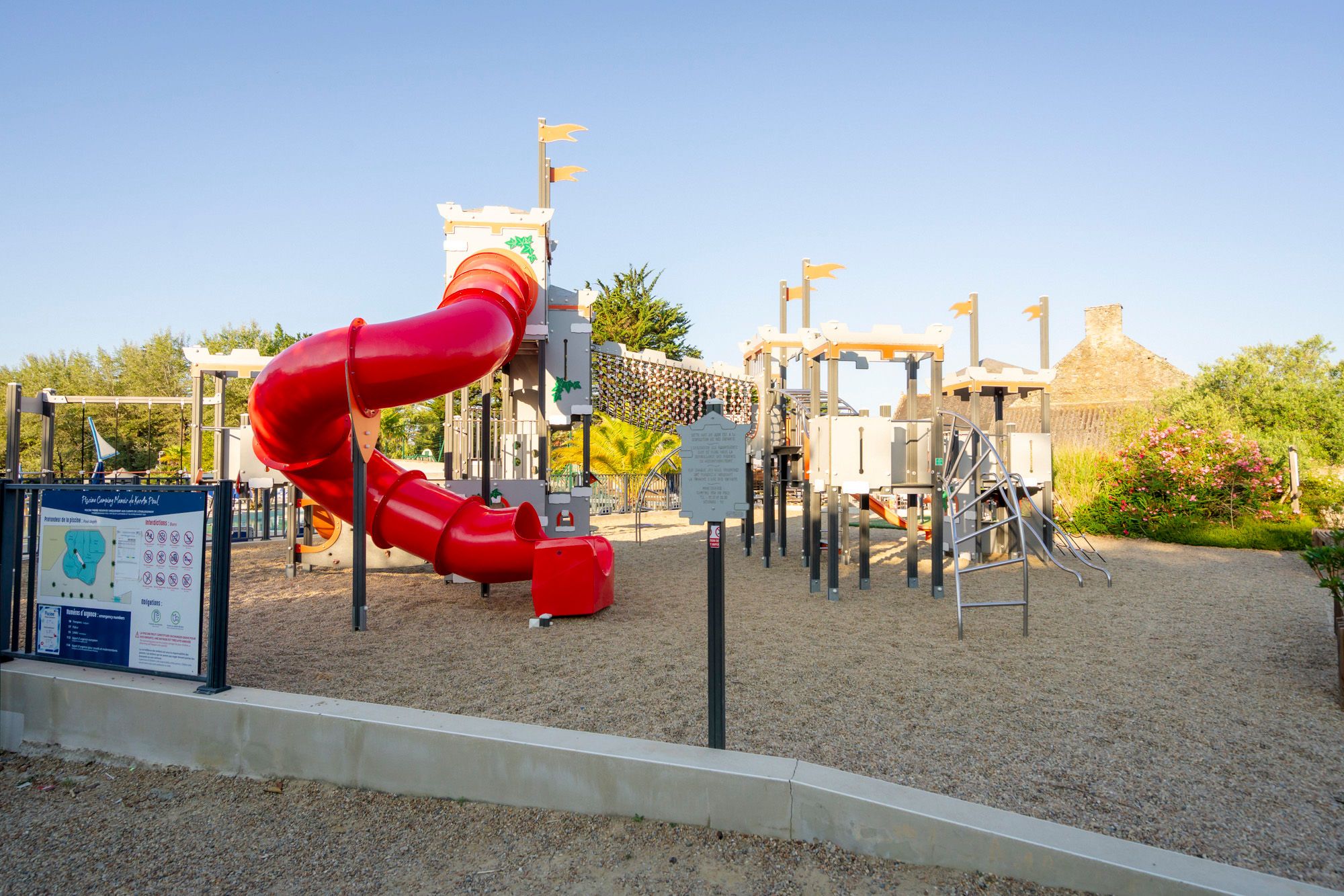 Ein Spielplatz mit einer roten Rutsche und verschiedenen Spielgeräten.