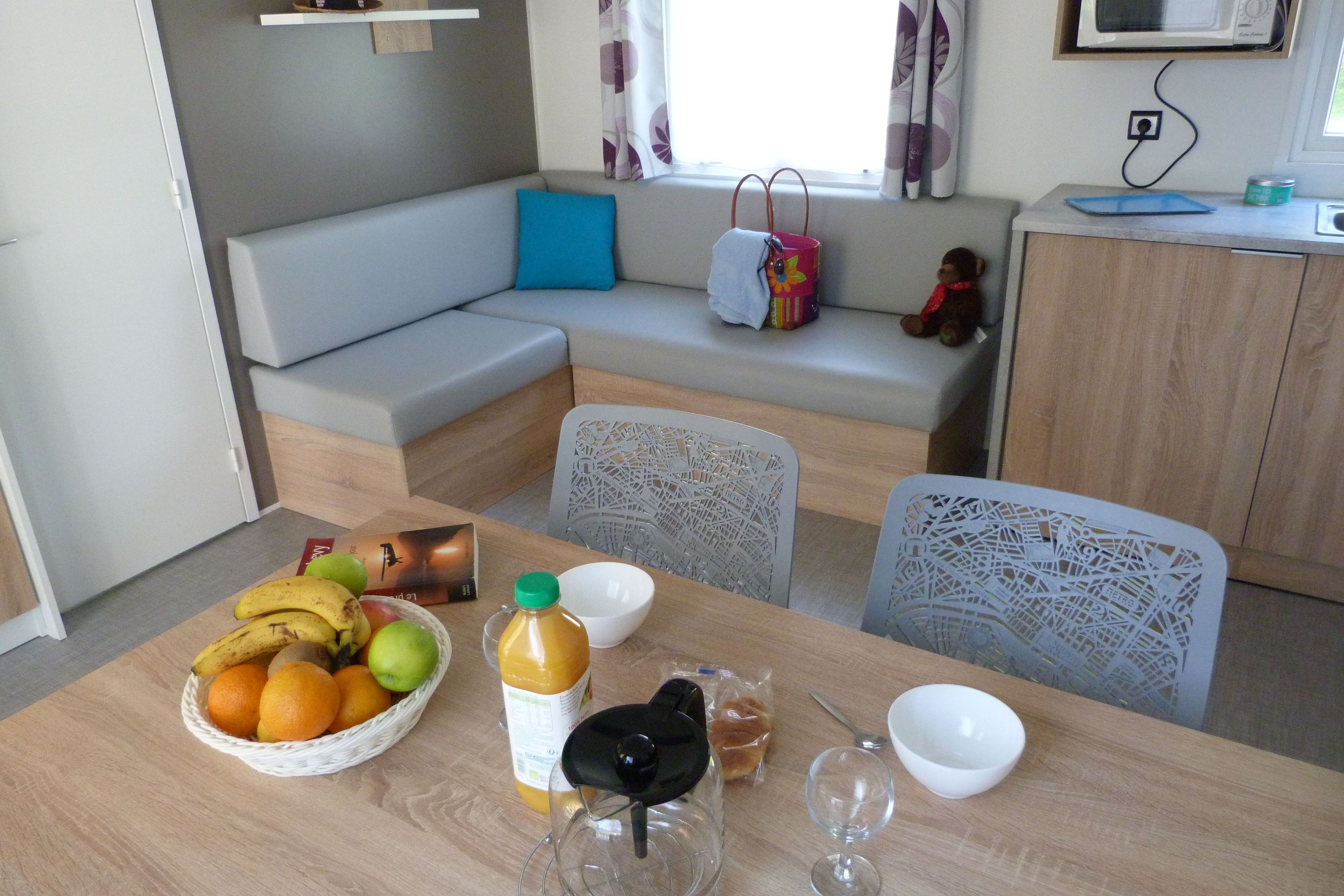 Un coin repas avec une table dressée pour deux personnes, un canapé et une fenêtre avec des rideaux.