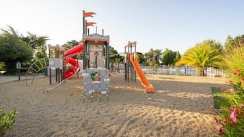 Un parque infantil con un tobogán rojo y estructuras para escalar.