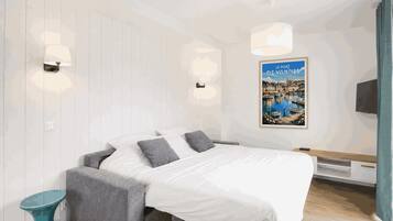 Une chambre à coucher moderne avec un lit, des tables de chevet, un téléviseur fixé au mur et une affiche.