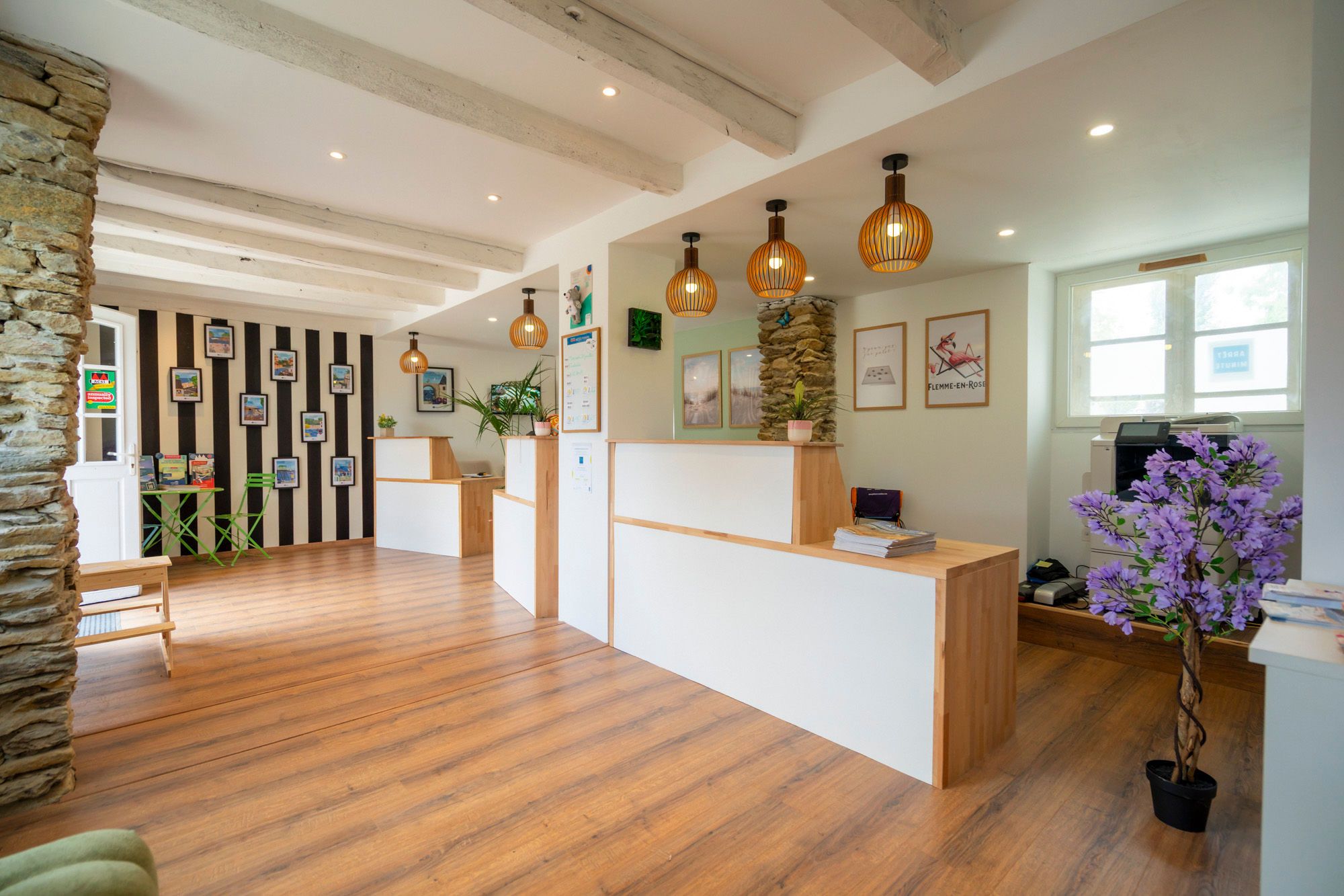 Un espace d’accueil comprenant un comptoir de réception en bois, un pilier en pierre et une plante en pot.