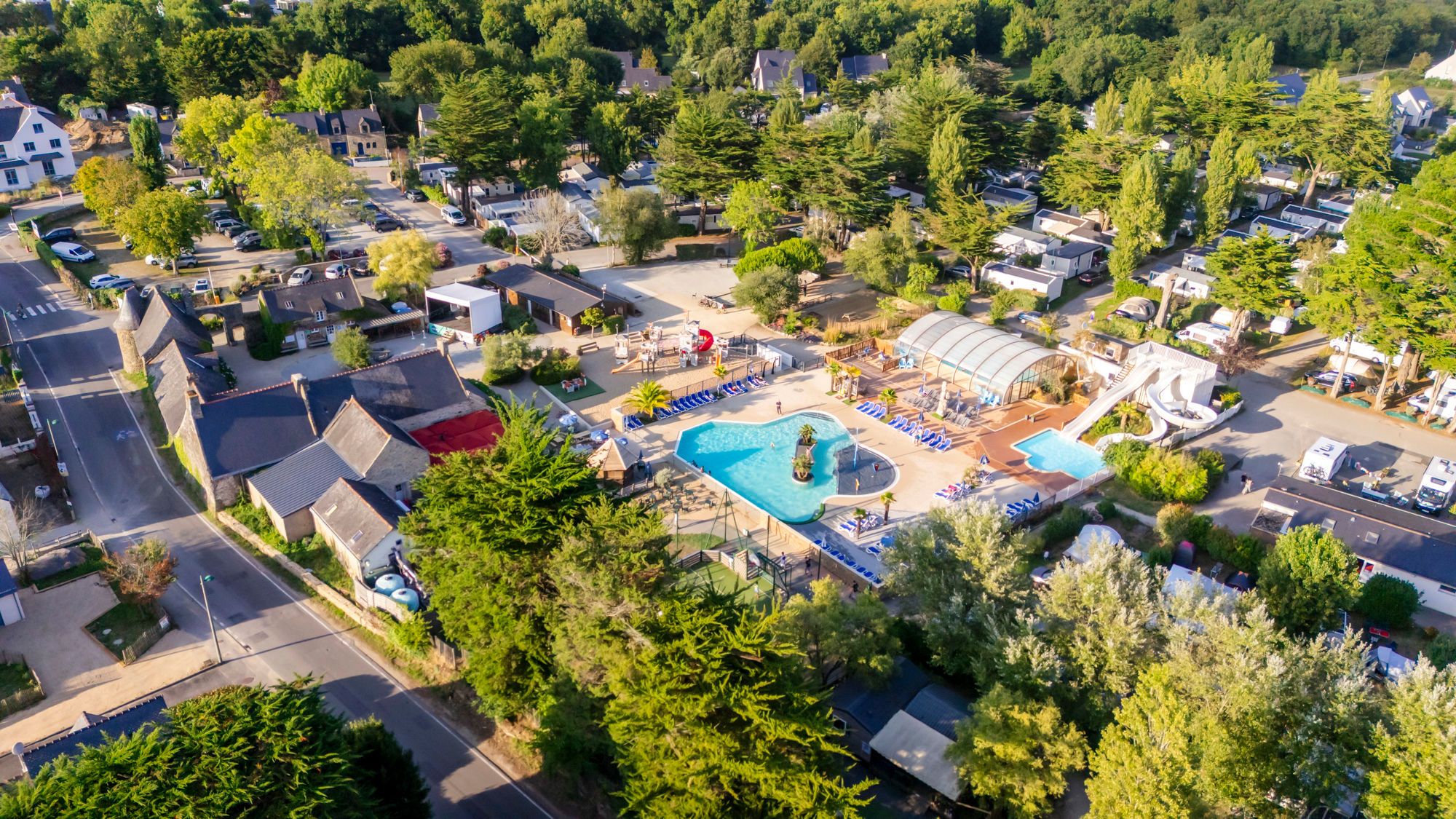 Vue aérienne d’un quartier résidentiel avec une piscine, un espace extérieur couvert et plusieurs maisons mobiles.
