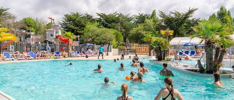 Zona de piscina con varias pistas de natación, sillas de descanso y palmeras.
