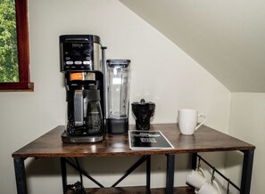 Une machine à café, une verseuse en verre et une tasse sur une table en bois.