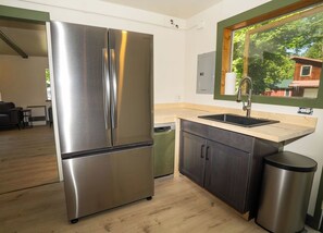 Een moderne keuken met een roestvrijstalen koelkast, een houten werkblad, een spoelbak en een vuilnisbak.