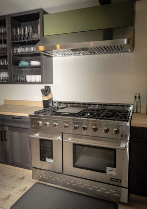 A stainless steel NXR range with a built-in oven and a separate stovetop, a knife block, and a glassware shelf. - Beautiful & quiet 3-bedroom house in downtown Talkeetna perfect for any getaway (Talkeetna)