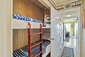 A bunk bed with a wooden ladder and patterned bedding. - Front Beach Isle of Palms Sea Cabin! (Isle of Palms)