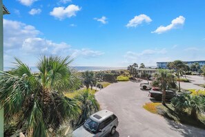 A parking area with a view of the ocean and a building in the background. - Front Beach Isle of Palms Sea Cabin! (Isle of Palms)