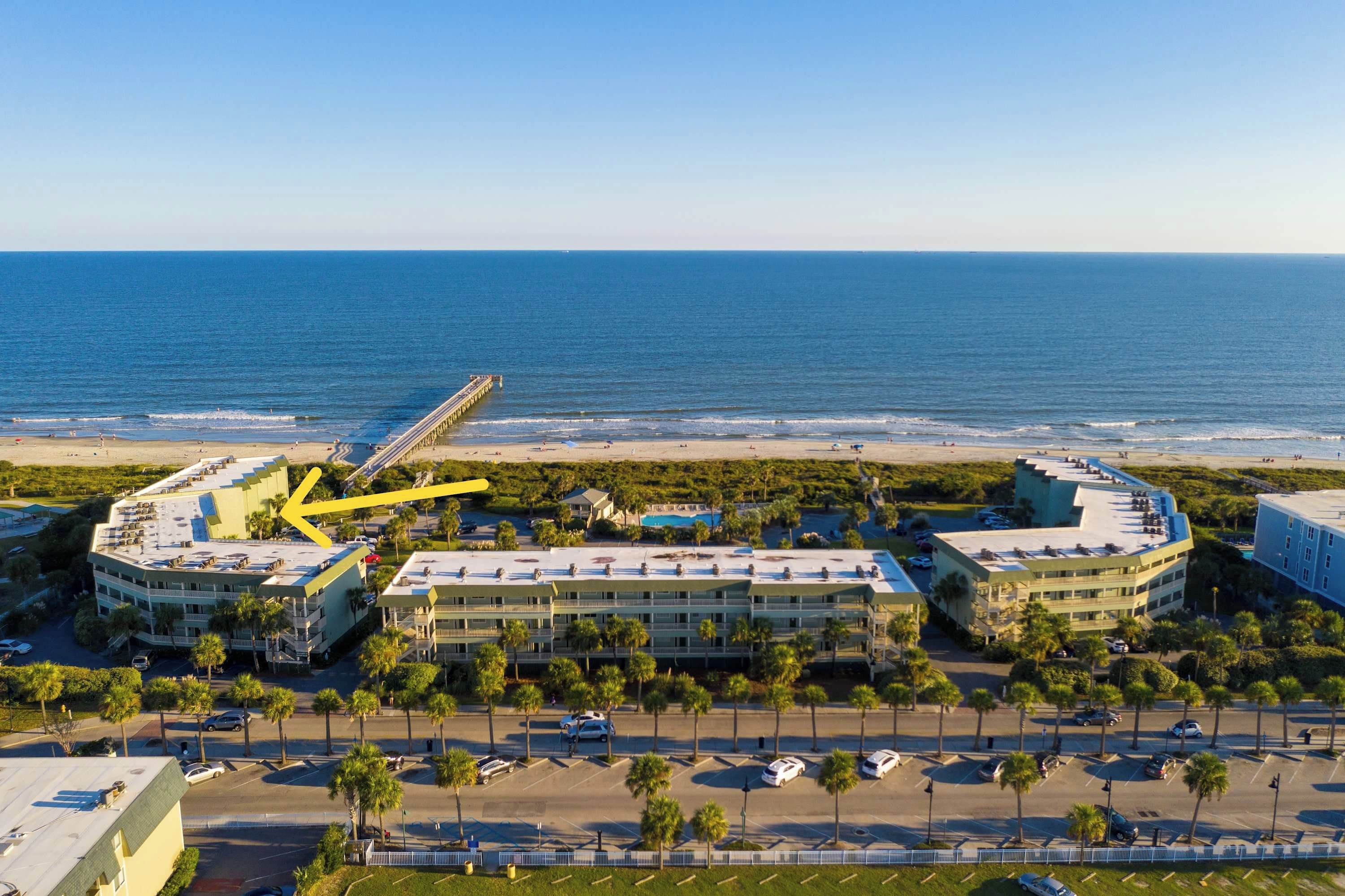 Un hôtel situé sur la côte, avec vue sur la plage, disposant d’un parking et d’une promenade bordée de palmiers.