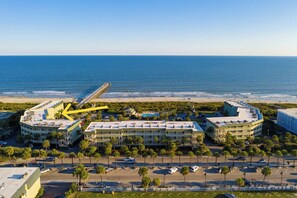 A coastal hotel with a beachfront view, featuring a parking lot and a promenade lined with palm trees. - Front Beach Isle of Palms Sea Cabin! (Isle of Palms)