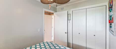 Un dormitorio con una cama, ventilador de techo y armario.