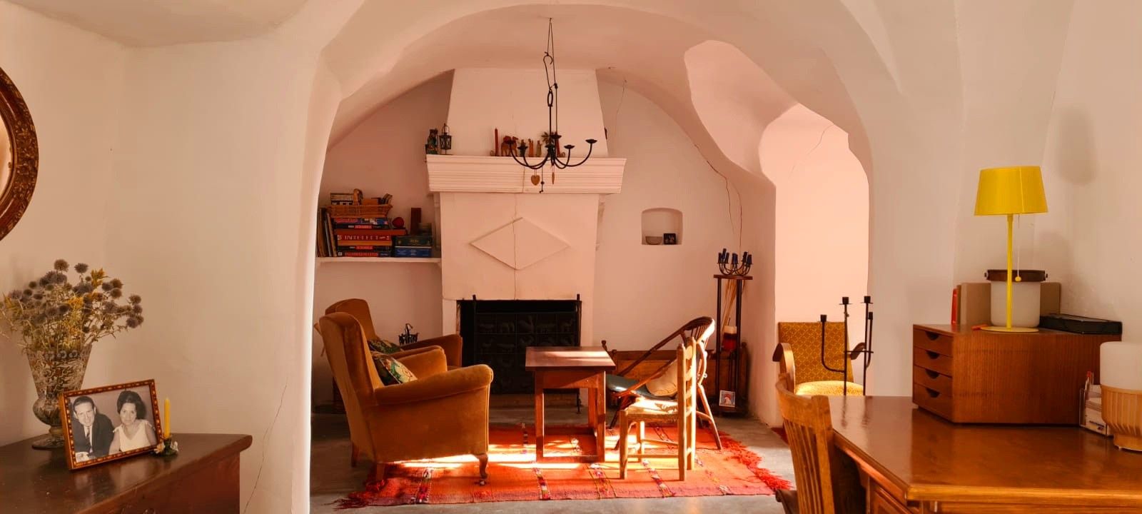 A cozy living room with a fireplace, comfortable seating, and a bookshelf.