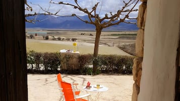Una puerta que da a un espacio al aire libre con una mesa, sillas y vistas a montañas.