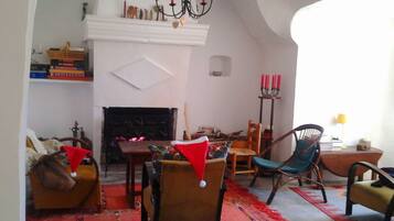 A cozy living room with a fireplace, a chandelier, and a red carpet.