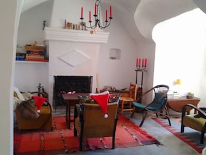 A cozy living room with a fireplace, a chandelier, and a red carpet. - Charming Cave in Andalusia with Private Terrace and Garden (Fuente Nueva)