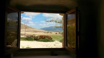 Una ventana con vista a un paisaje, que incluye una colina y un cielo despejado.