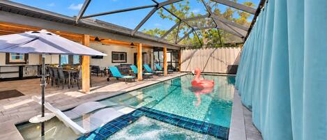 Piscina com hidromassagem, espreguiçadeiras e boia de flamingo.