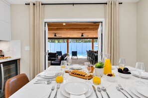 A dining area with a table set for breakfast, including plates, cutlery, and a fruit bowl. - Casa Lumina | 6 Bedroom Luxury Estate | Pool, Spa & Outdoor Kitchen (Temple Terrace)
