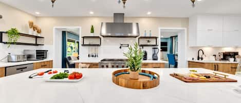 A modern kitchen with a central island, built-in appliances, and a decorative ceiling light fixture.