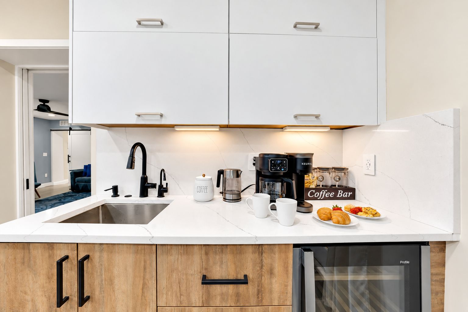 A modern kitchen with white cabinets, a coffee station, and a dishwasher.